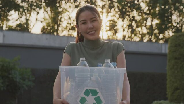 Save the planet reduce CO2 go green people carry bin box at outdoor nature, reuse clean sort waste symbol. Global Earth protect day net zero eco friendly happy asia woman smiling looking at camera.