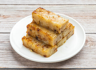 fried white turnip cake served in dish isolated on wooden table top view hong kong food