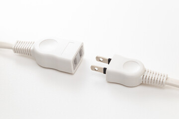 白背景に置かれた電源プラグの延長コード