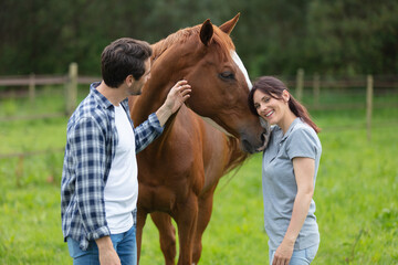 happy loving couple spending time with horses on ranch