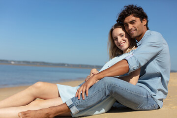 young couple sitting together on a sand by sea