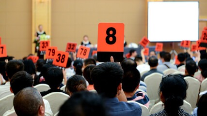 Crowd of bidders holding their numbered bidding paddles at an auction