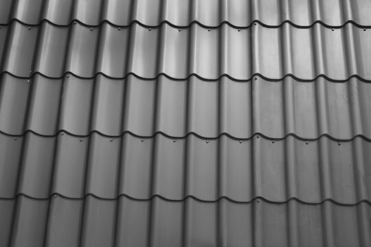 Fragment of modern metal roof tiles. Metallic grey roof with screws. background of Macro image.