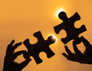 two hands of businessman to connect couple puzzle piece with sky background. Jigsaw alone wooden...