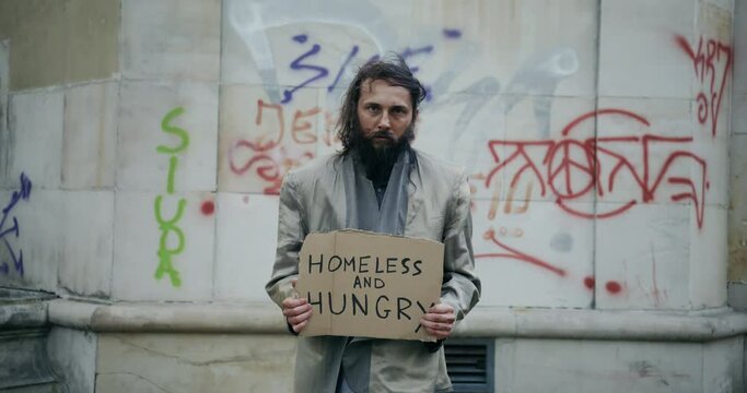 Slow Motion video of a homeless and scruffy man begging for money or food so then he can eat and survive for the day.