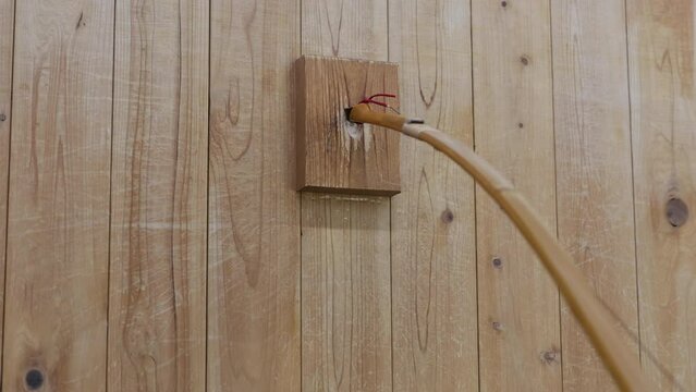 Stringing a Japanese yumi bow for kyudo japanese archery in wall stringing block.