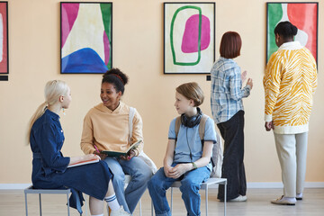 Diverse group of teenagers enjoying discussion in modern art gallery or museum