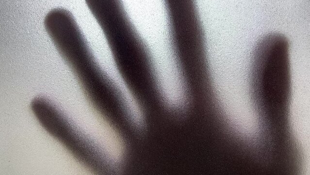 Male hand silhouette shadow behind translucent mirror sliding slowly