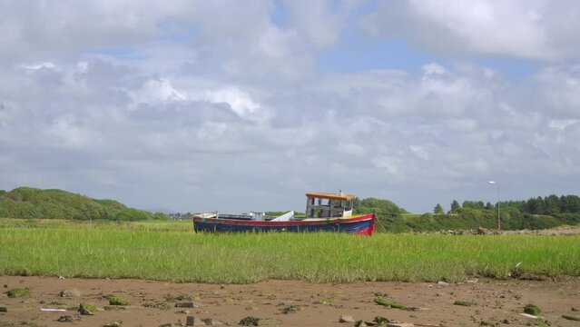 Old shipwreck beached on grass with fast moving clouds and cloud shadows. Time lapse 30x.