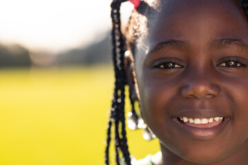 Portrait of happy african american schoolgirl on sports field at elementary school, copy space