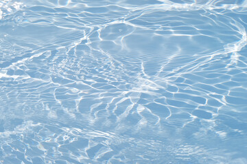 Blue water with ripples on the surface. Defocus blurred transparent blue colored clear calm water surface texture with splashes and bubbles. Water waves with shining pattern texture background.