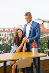 Fototapeta premium Stylish couple in love at a table in a street cafe communicates and flirts with each other