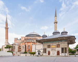 Fototapeta na wymiar 17th century Turkish rococo water fountain of Sultan Ahmed III, or Ahmet Cesmesi, with Hagia Sophia in the far end, in the Great Square, near the Imperial Gate of Topkapi Palace, Istanbul, Turkey