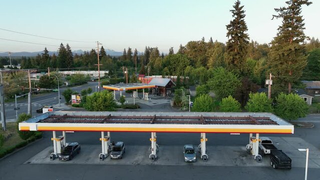 Drone shot pulling away from cars filling up at a gas station.