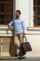 Fototapeta na wymiar Handsome businessman walking on the street, with luxury brown leather briefcase. Fashionable style.