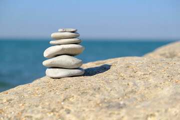 Fototapeta premium Pebble tower balance harmony stones arrangment on sea beach coastline. Spa therapy summer travel vacation.