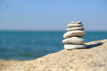 Fototapeta na wymiar Pebble tower balance harmony stones arrangment on sea beach coastline. Spa therapy summer travel vacation.
