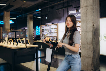 Smiling woman choosing electric scooter in shop