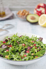 A plate with green rocket salad with pomegranate and avocado