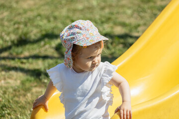 toddler girl on the slide, having fun on sunny day at playground