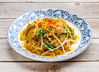 stir-fried rice vermicelli in singapore style served in dish isolated on wooden table top view hong kong food