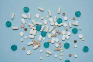 Tablets in bulk are multicolored on a blue background. The concept of medicine, pharmacy.