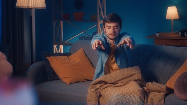 Male sleepwalker sits on a sofa in the living room. Somnambulism.