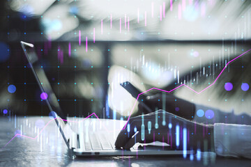 Side view of male hands using laptop keyboard and cellphone at outdoor workplace with glowing candlestick forex chart on blurry backdrop. Technology, trade and financial data concept. Double exposure.