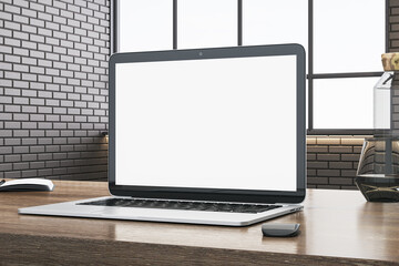 Fototapeta premium Close up of office desktop with empty white computer, supplies and other objects. Blurry brick wall and window with city view in the background. Mock up, 3D Rendering.