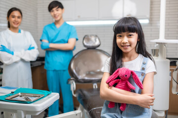 Children's dentistry for healthy teeth .Close-up  happy little child asian girl smiles looking at camera, sitting in dentist's chair, receiving dental.