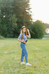 Attractive young woman with a camera in her hands is resting and taking pictures outdoors