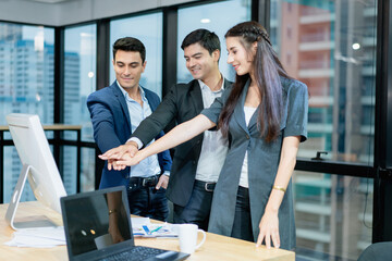 Group of young energetic business people joining hands in office city business cooperation concept in the background.