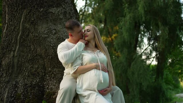 A loving man tenderly hugs his pregnant woman