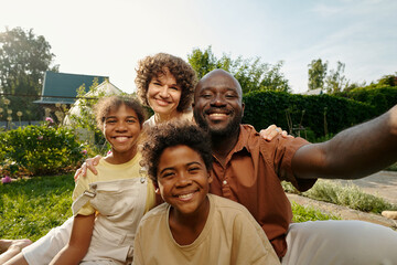 Happy interracial family looking at camera with smiles while young African American man with...