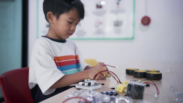 Kindergarten asian student learn in coding robot car and electronic board cable in STEM Arduino, Computer code in robotics for kids.