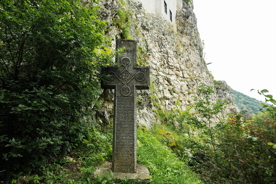 Old srone croos against Bran Castle in Romania. Dracula medieval castle in Carpathians, Transylvania.