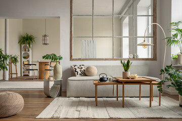 Creative composition of living room interior with modular sofa, beige rug, plants, vase with green leaves, pouf, stylish coffee table, big window, lamp and personal accessories. Home decor. Template.