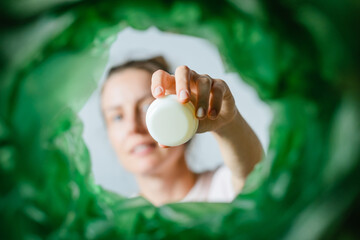 Low angle view woman sorting waste at cosmetic products recycling bin POV. Waste segregation, waste...