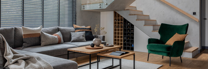 Modern living room interior design. Grey corner sofa, velvet armchair, coffee table and minimalist...