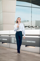 Business woman in pants and white blouse walking iand looking confident