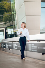 Business woman in pants and white blouse walking iand looking confident