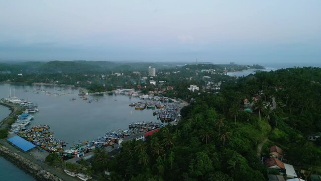 Fishery harbour on island in Indian ocean aerial view. Little colorful fishing boats moored in dockyard in Sri Lanka footage from drone. Small ships ancored in local fish market port top shot.