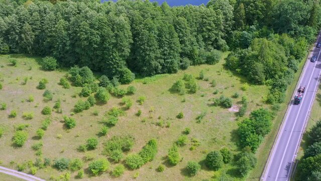 Aerial view of Forests and meadows along a country road with moderate traffic in Masuria, Poland