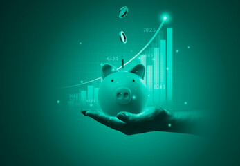 Hand holding piggy bank and  coins falling with increasing stock market graph chart for money saving and deposit of investment concept.