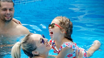 Mother and daughter resting and swimming in a pool in summer