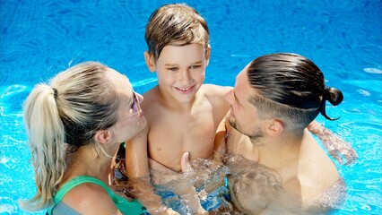 Mother with father and son resting and swimming in a pool in summer, happy family