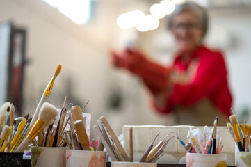 Woman enjoying creative process of pottery coloring in pottery workshop.