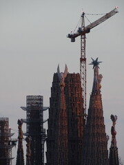 Construcci&oacute;n final de la bas&iacute;lica de la sagrada familia, en Barcelona, monumento dise&ntilde;ado por Antoni Gaud&iacute;, con gr&uacute;a y a el atardecer