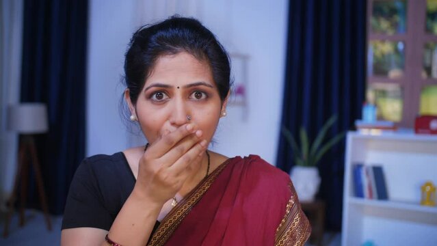 An attractive middle-aged woman in traditional Indian dress with surprise look. An Indian housewife in traditional clothing covers her mouth with her hand out of shock - facial expressions  naughty...