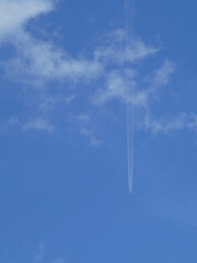 Plane with vapour trails in a blue sky as background